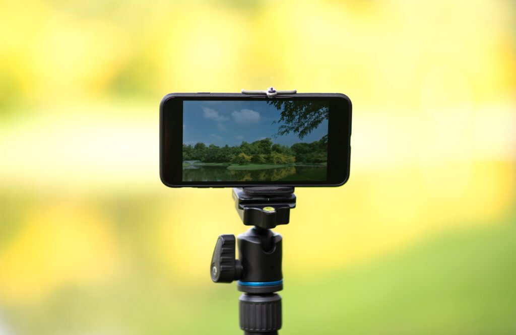 See it with your own eyes. Smartphone attached to a selfie stick showing asian forest landscape. Copy space on the right and on the left side